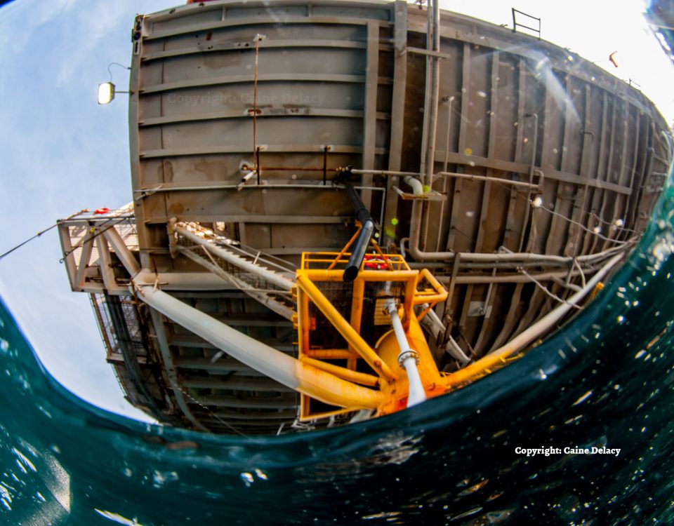 A photo of the underside of an oil rig, taken just beneath the surface of the water