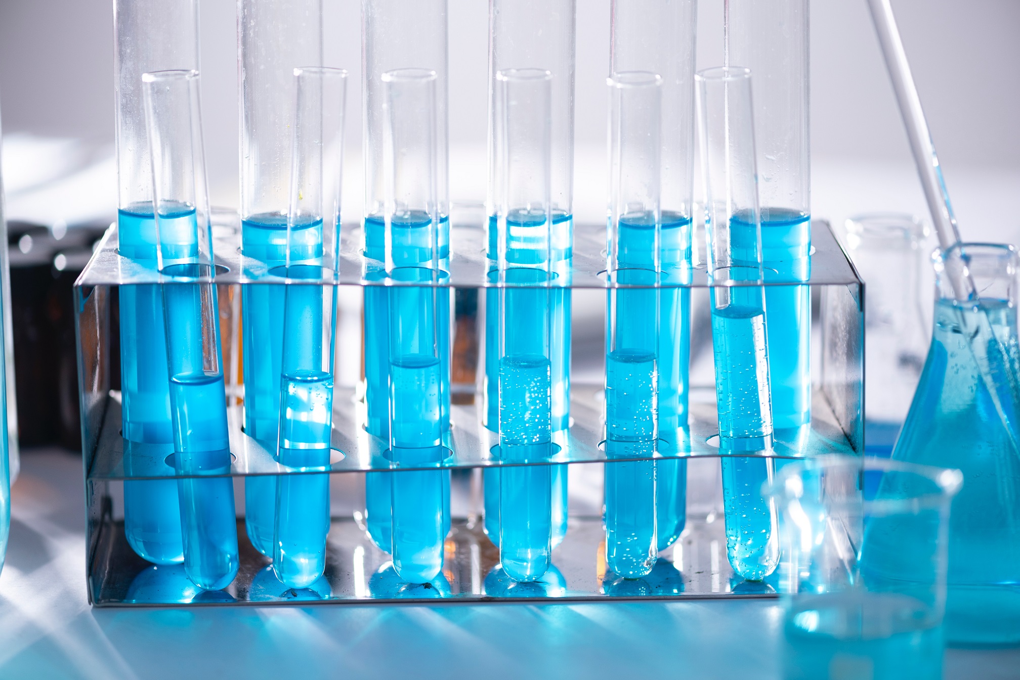 Vials of blue liquid are lined up on a lab table